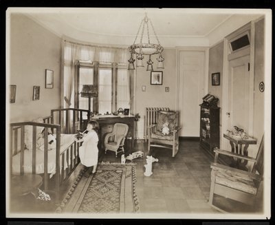 A girl holding a candle, climbing into a crib, in a bedroom of the A.C. Cronin residence by Byron Company
